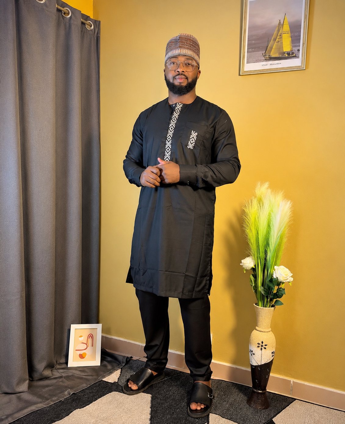 Tunique noire, plastron et poche brodés d'un motif géométrique blanc. Avec pantalon assorti.