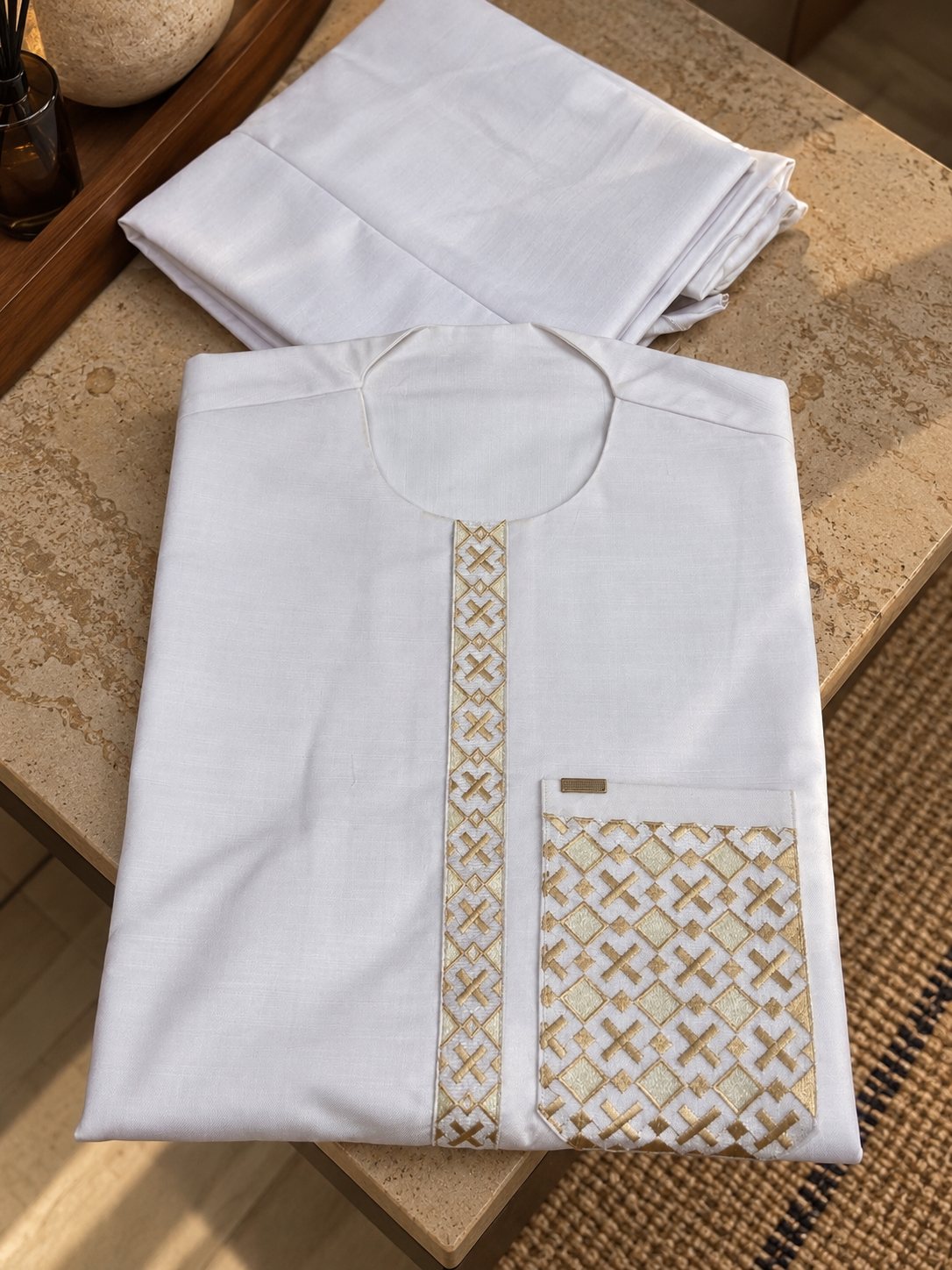 Blanc, plastron et poche entièrement brodés de croix et de losanges dorés.
