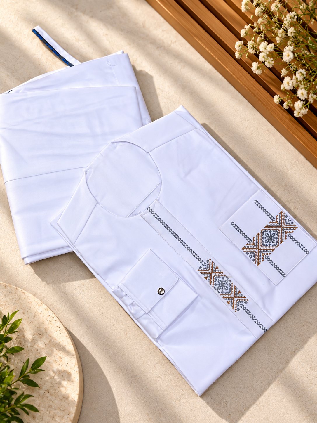 Blanc, plastron et poche brodés de motifs croisés gris et cuivre.