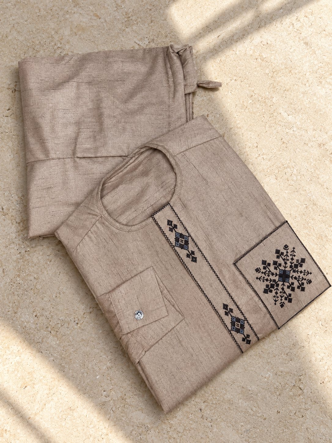 Moka texturé, motifs brodés noirs et bleus en forme d'étoile sur le plastron et la poche.